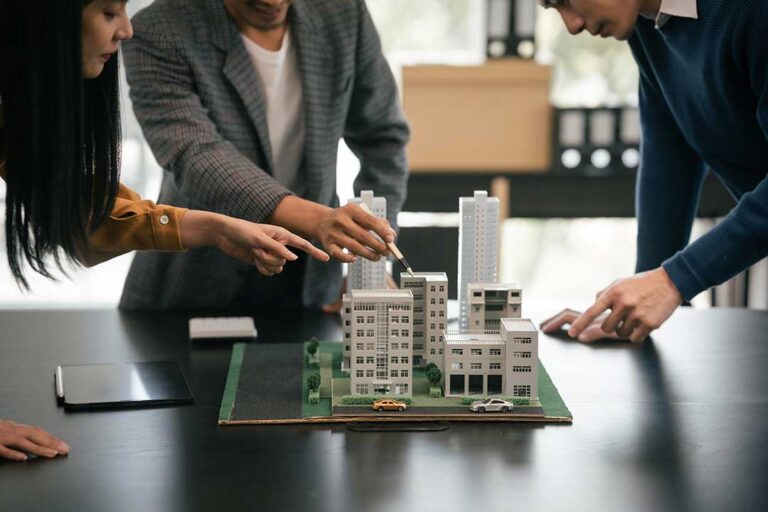 A couple reviews property documents with a real estate agent at a table.