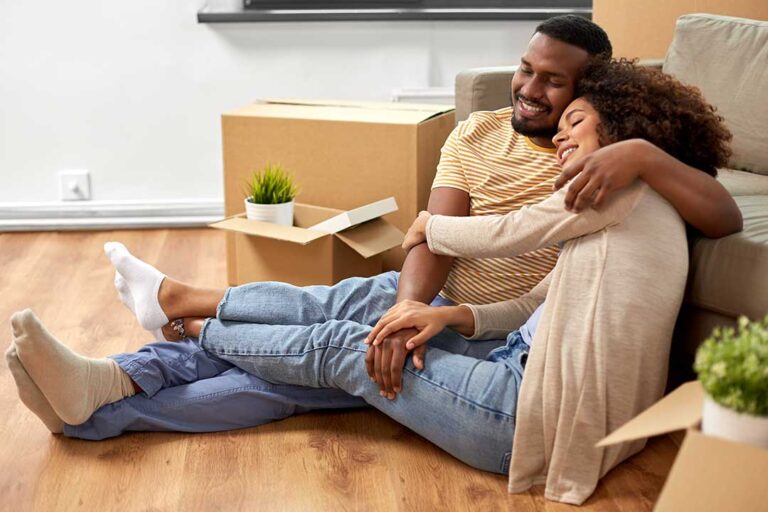 A couple and closing agent review documents at a kitchen table during a home purchase.